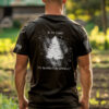 Model wearing black t-shirt with Appeal to Heaven flag design featuring a bold White Pine Tree over a distressed American flag background. Historic patriotic graphic with strong revolutionary symbolism.