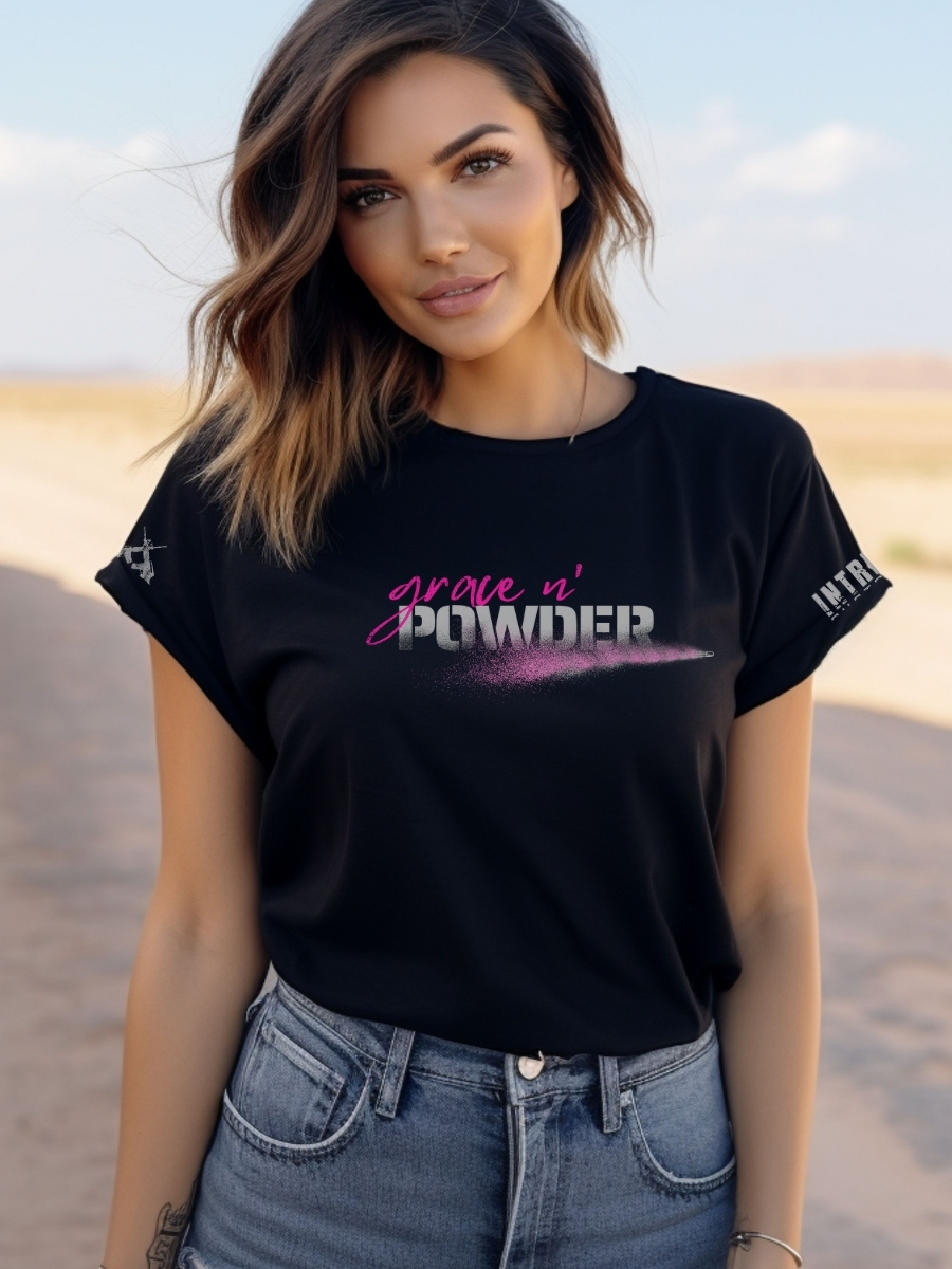 Model wearing the women's black Grace N' Powder T-shirt with bold hot-pink "Grace N' Powder" logo and powder-blast graphic.