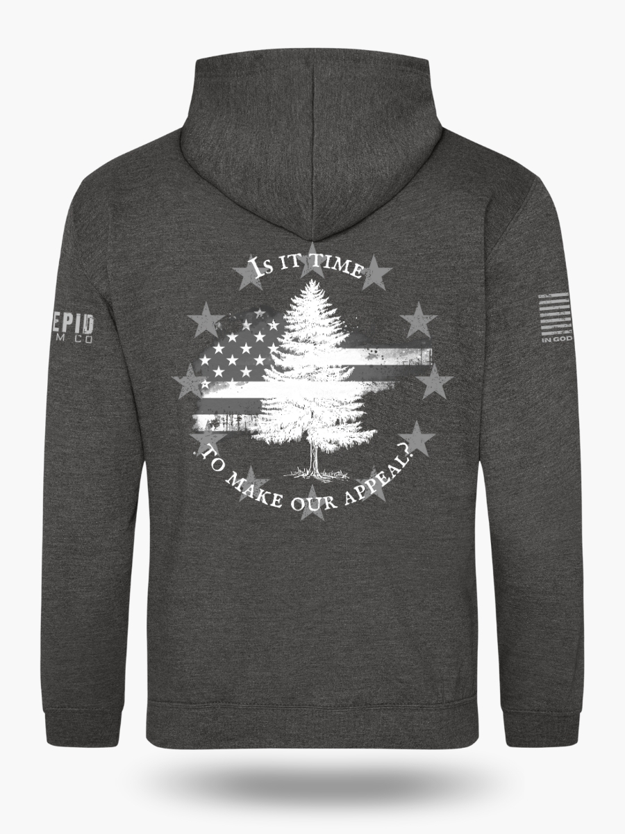 Dark heather grey hoodie with Appeal to Heaven flag design featuring a bold White Pine Tree over a distressed American flag background. Historic patriotic graphic with strong revolutionary symbolism.