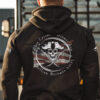 Model wearing black patriotic hoodie inspired by Revolutionary privateers, featuring pirate skull, swords, and anti-tyranny text over a worn U.S. flag.