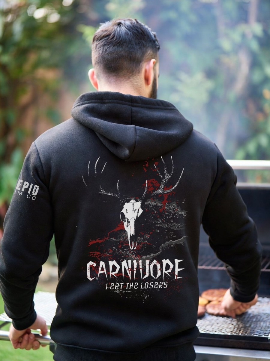 Man wearing black hoodie featuring a fierce deer skull graphic with the words &acirc;Carnivore &acirc; I Eat the Losers.&acirc; Warm, rugged hunting hoodie for outdoor enthusiasts.